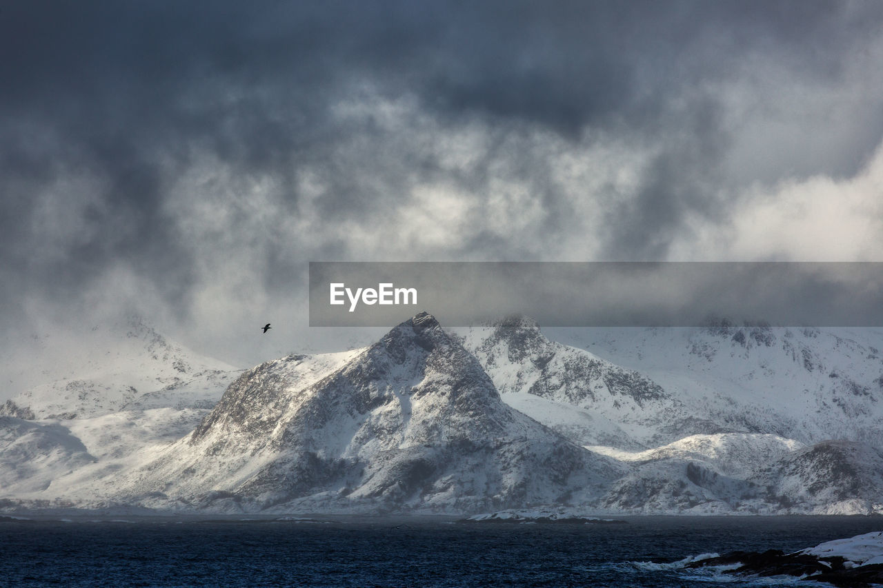 Scenic view of snowcapped mountains by sea during winter