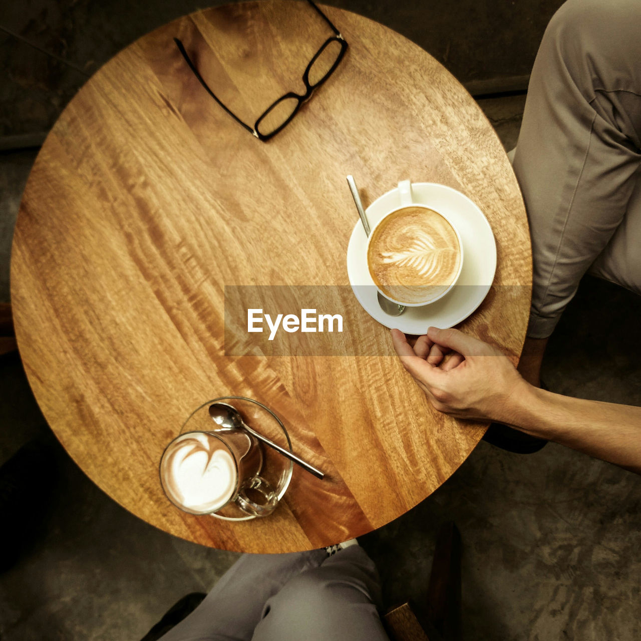 High angle view of people by wooden table with coffee cups