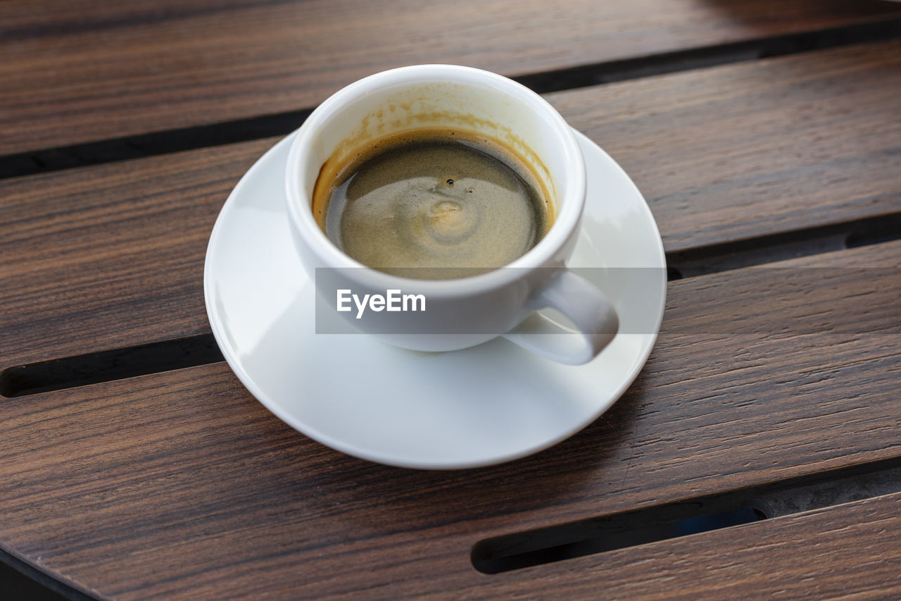 HIGH ANGLE VIEW OF COFFEE CUP ON WOODEN TABLE