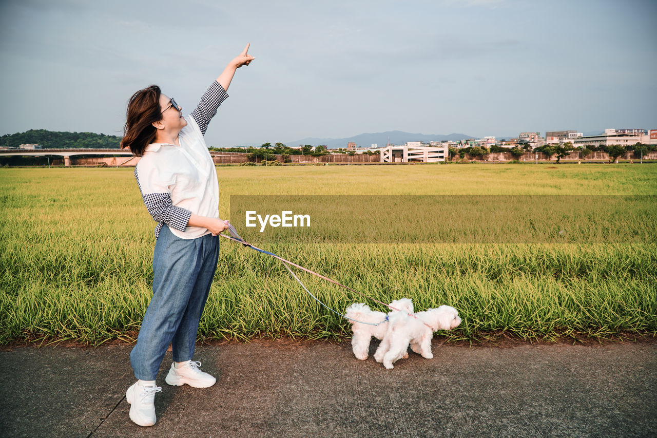 Full length of woman standing with dogs by land