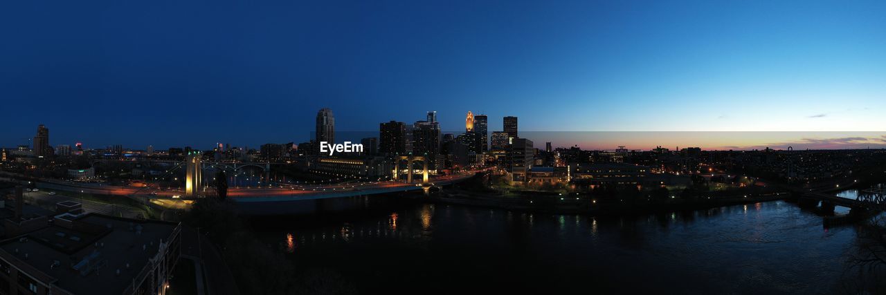 Illuminated buildings in city against clear sky at night