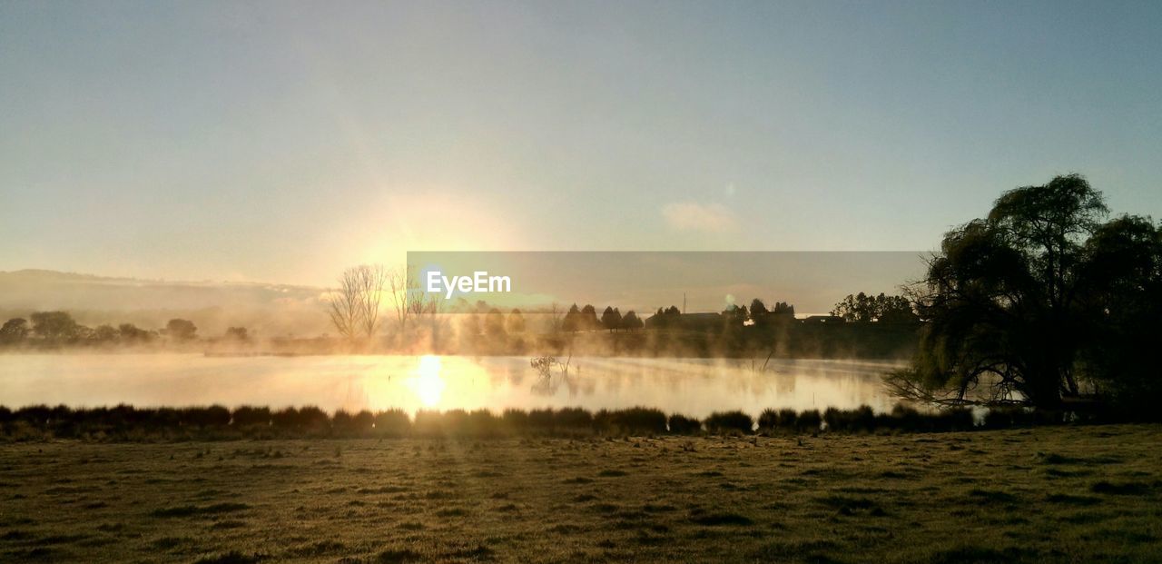 Scenic view of calm lake against sky during sunrise