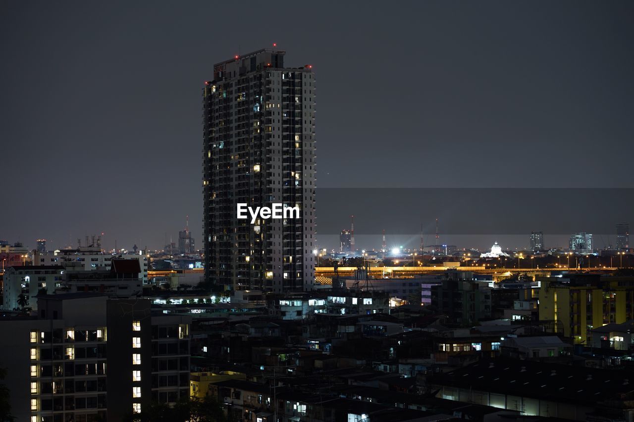 ILLUMINATED MODERN BUILDINGS AGAINST SKY AT NIGHT