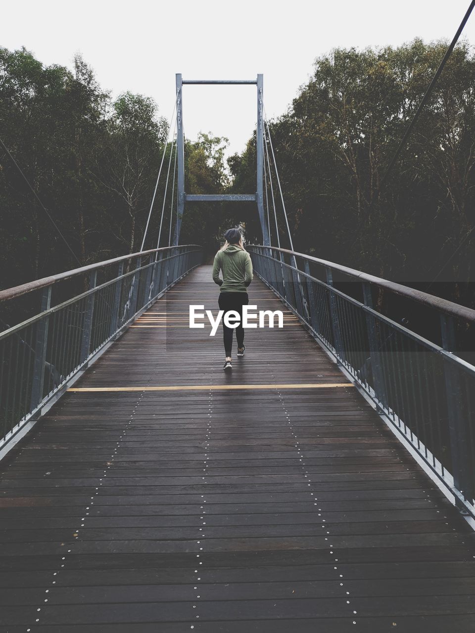 Rear view of woman walking on footbridge