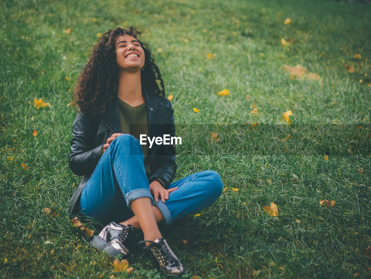 Cheerful young woman sitting on grass