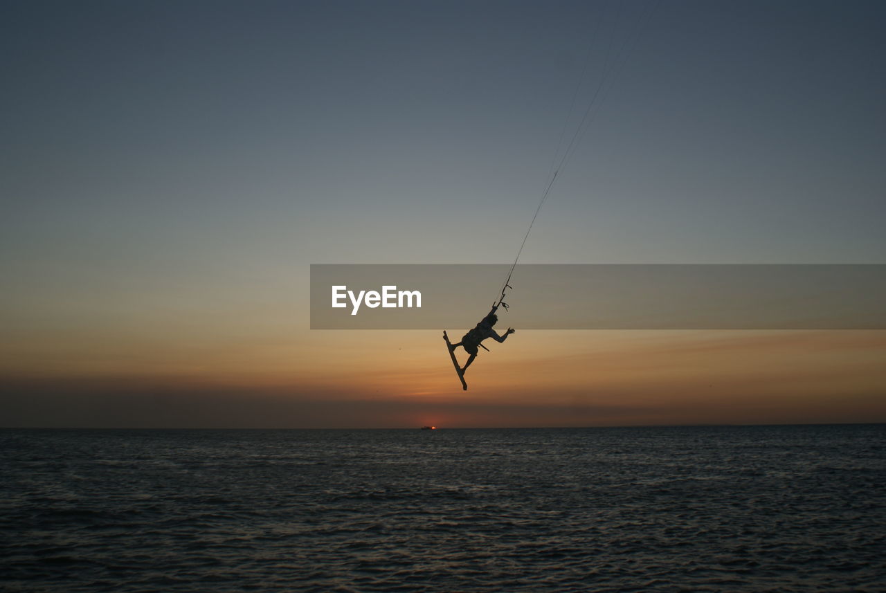 Silhouette bird flying over sea against clear sky