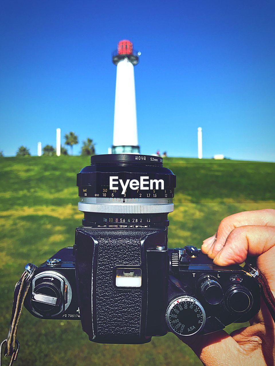 Cropped image of man holding camera against lighthouse
