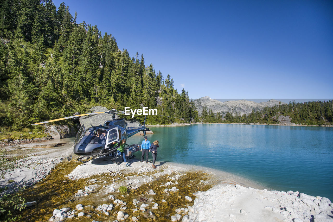 Tourist group arrives at lake via helicopter for adventure tour.