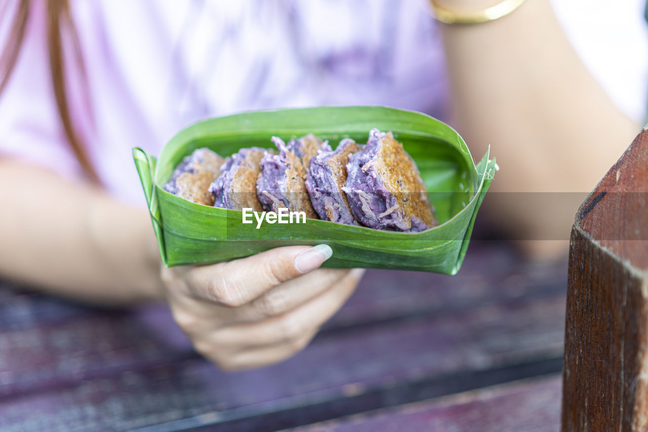 CLOSE-UP OF HAND HOLDING PURPLE LEAF