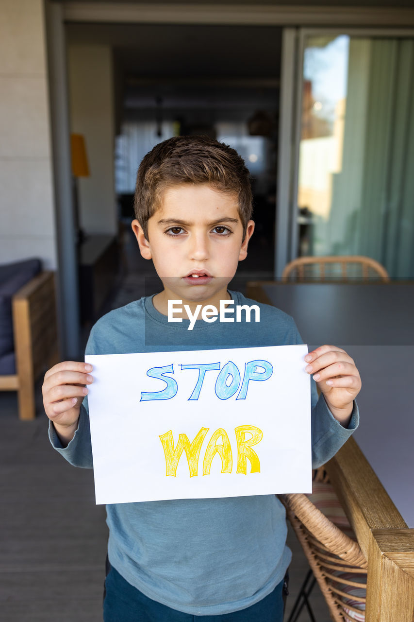 Little kid showing stop war on a paper. ukraine russia war concept.