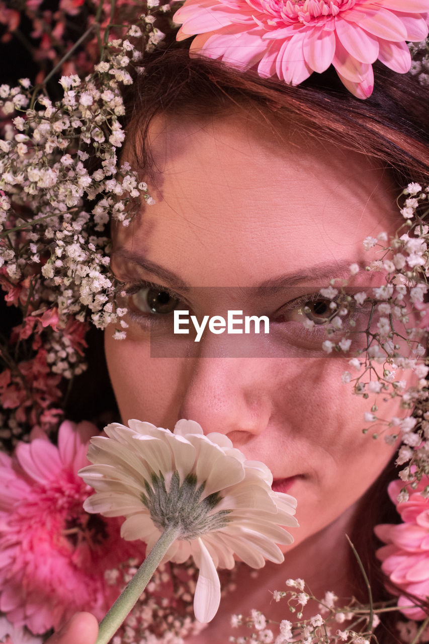 Close-up portrait of beautiful woman smelling flowers