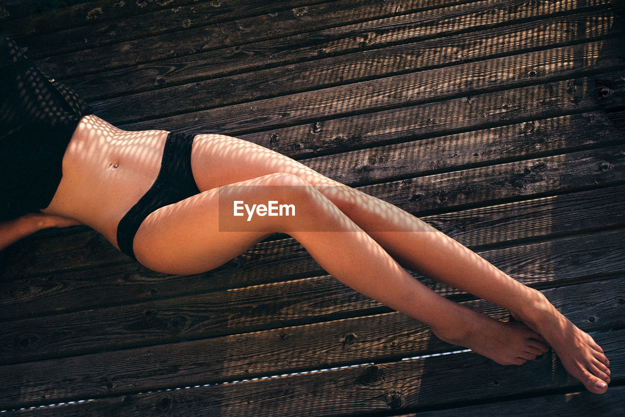 High angle view of seductive woman lying down on wooden floor