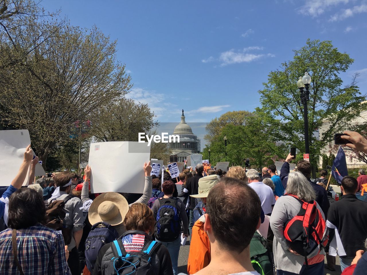 Rear view of crowd protesting at capitol building against sky