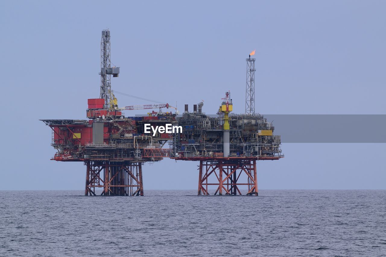 Drilling rig in sea against clear sky