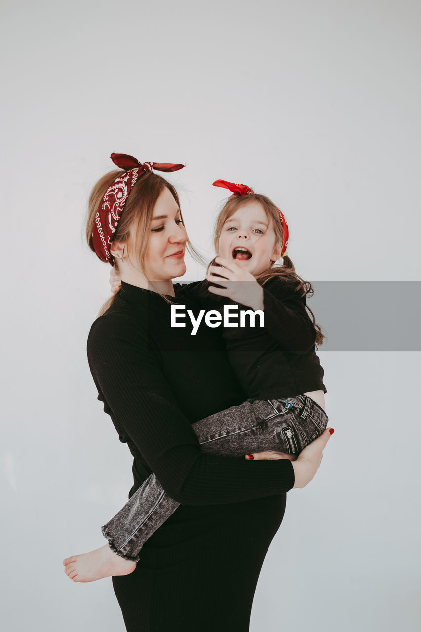 Smiling mother with daughter against white background