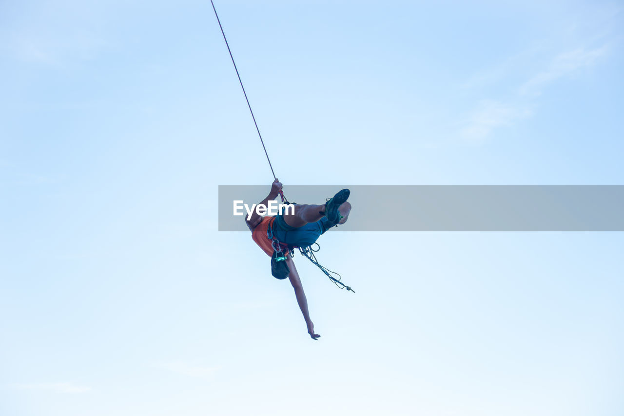 LOW ANGLE VIEW OF MAN WITH ROPE AGAINST SKY