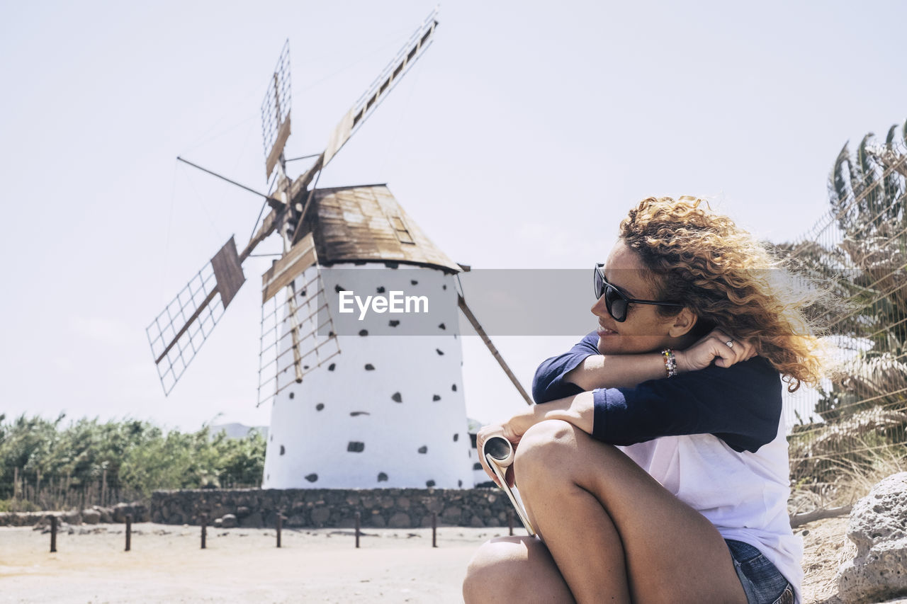 Woman sitting against traditional windmill in city