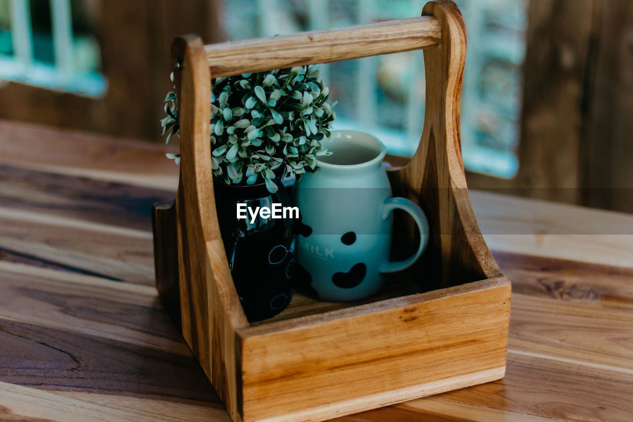 Close-up of plant with container in wooden tray on table