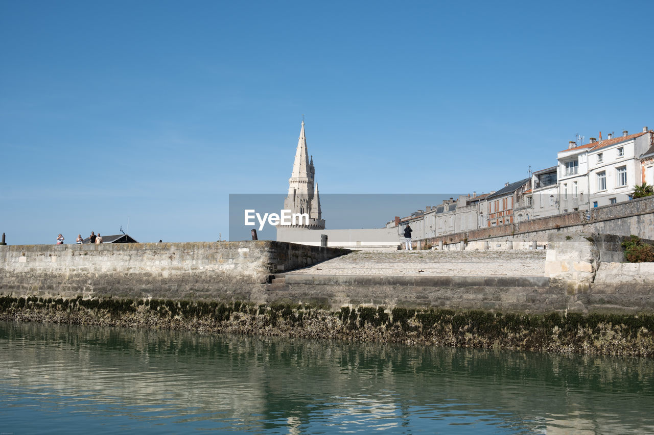 architecture, water, built structure, reflection, building exterior, sky, travel destinations, nature, building, sea, blue, place of worship, travel, religion, clear sky, history, landmark, tower, the past, tourism, city, sunny, day, belief, waterfront, no people, outdoors, copy space, waterway, spirituality