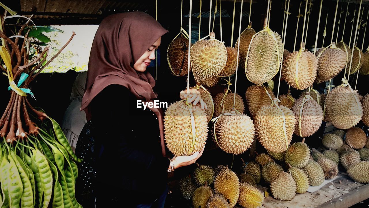 Smiling woman holding fruit at stall