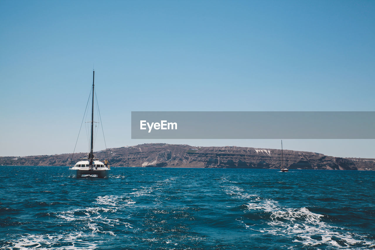 Boat sailing in blue sea against clear sky on sunny day