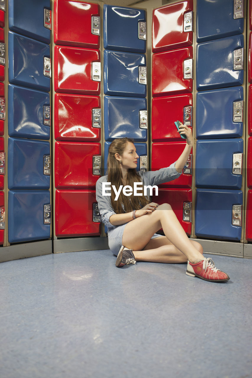 A young woman by some red and blue lockers.