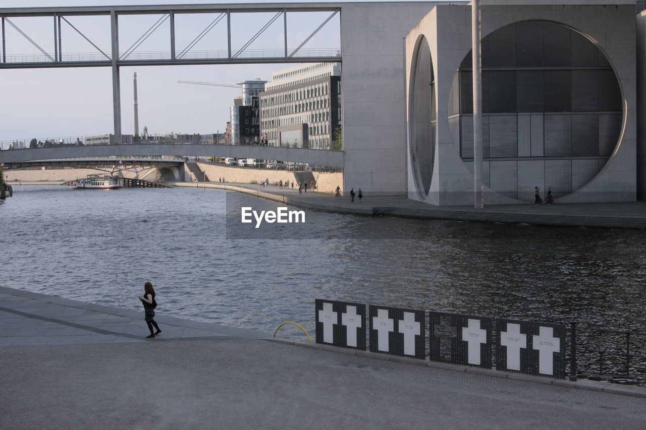 Rear view of man standing on bridge over river