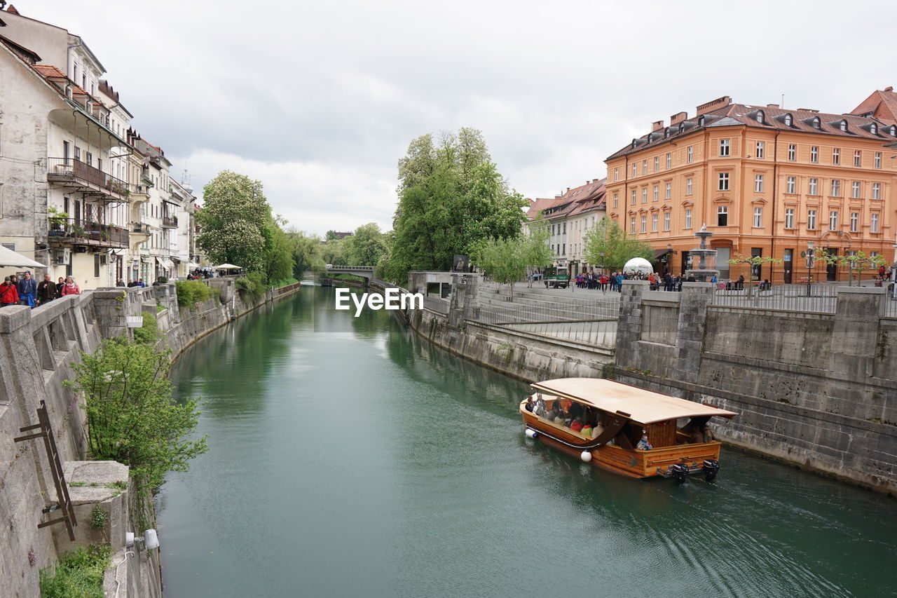 Passenger boat in canal amidst city