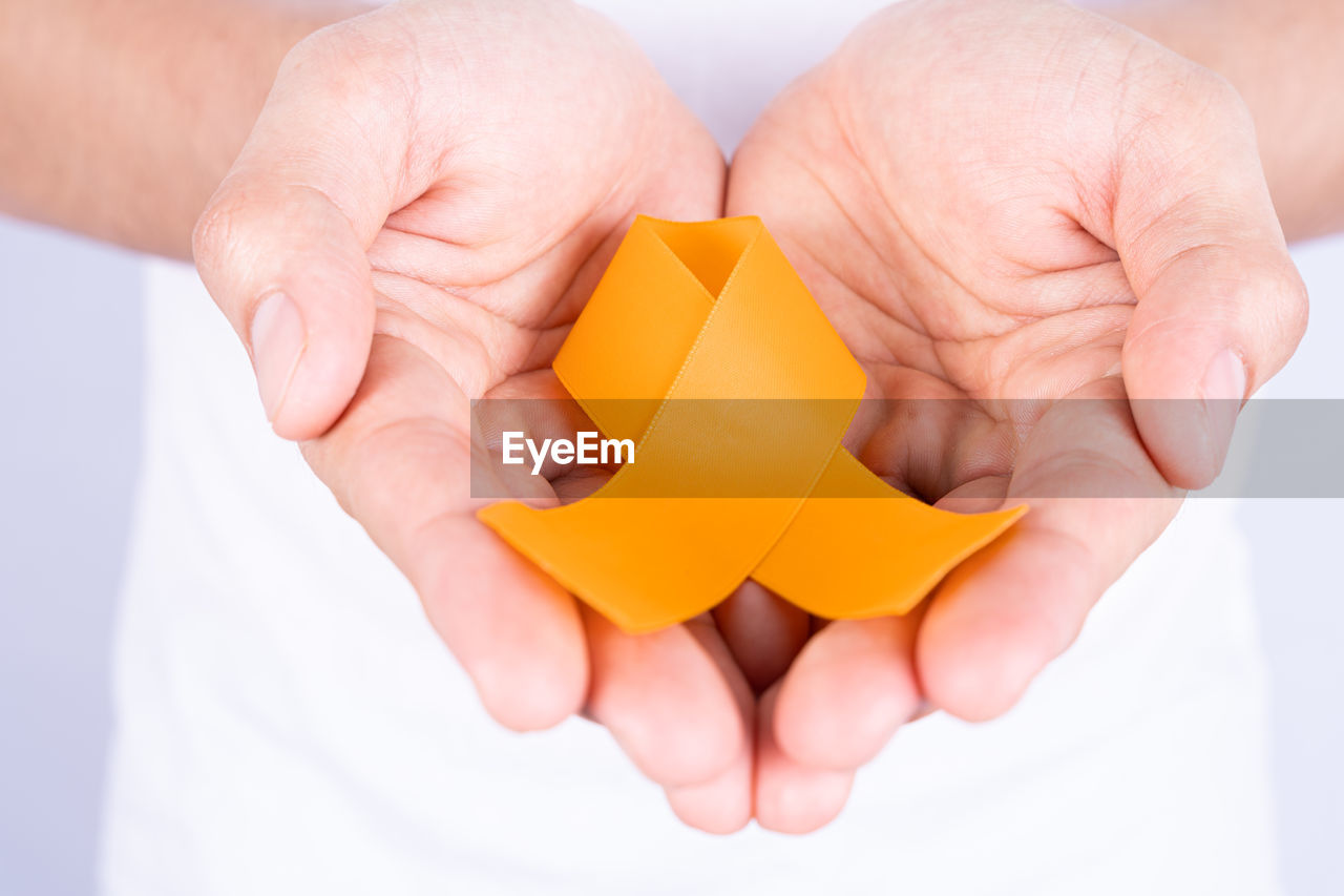 MIDSECTION OF MAN HOLDING ORANGE