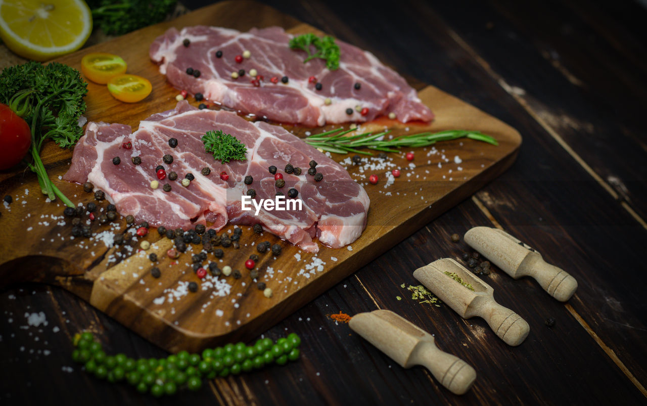 Top view - pork meat steaks with wood dark background, steaks on a wood cutting board with herbs, 