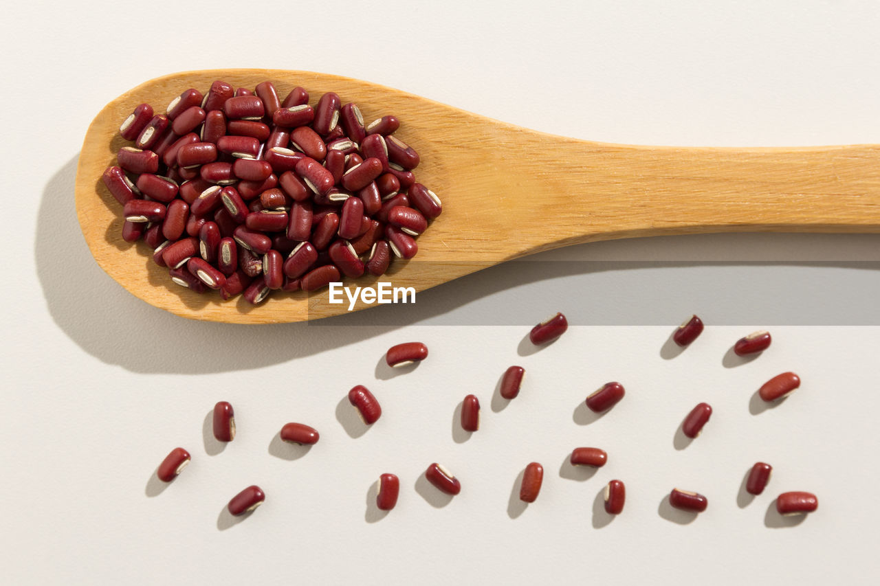 Close-up of kidney beans in wooden spoon against white background