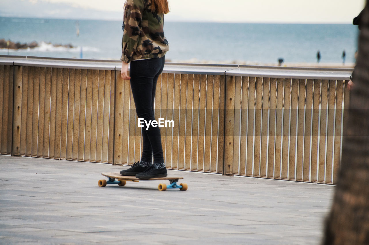 Low section of woman skateboarding on promenade
