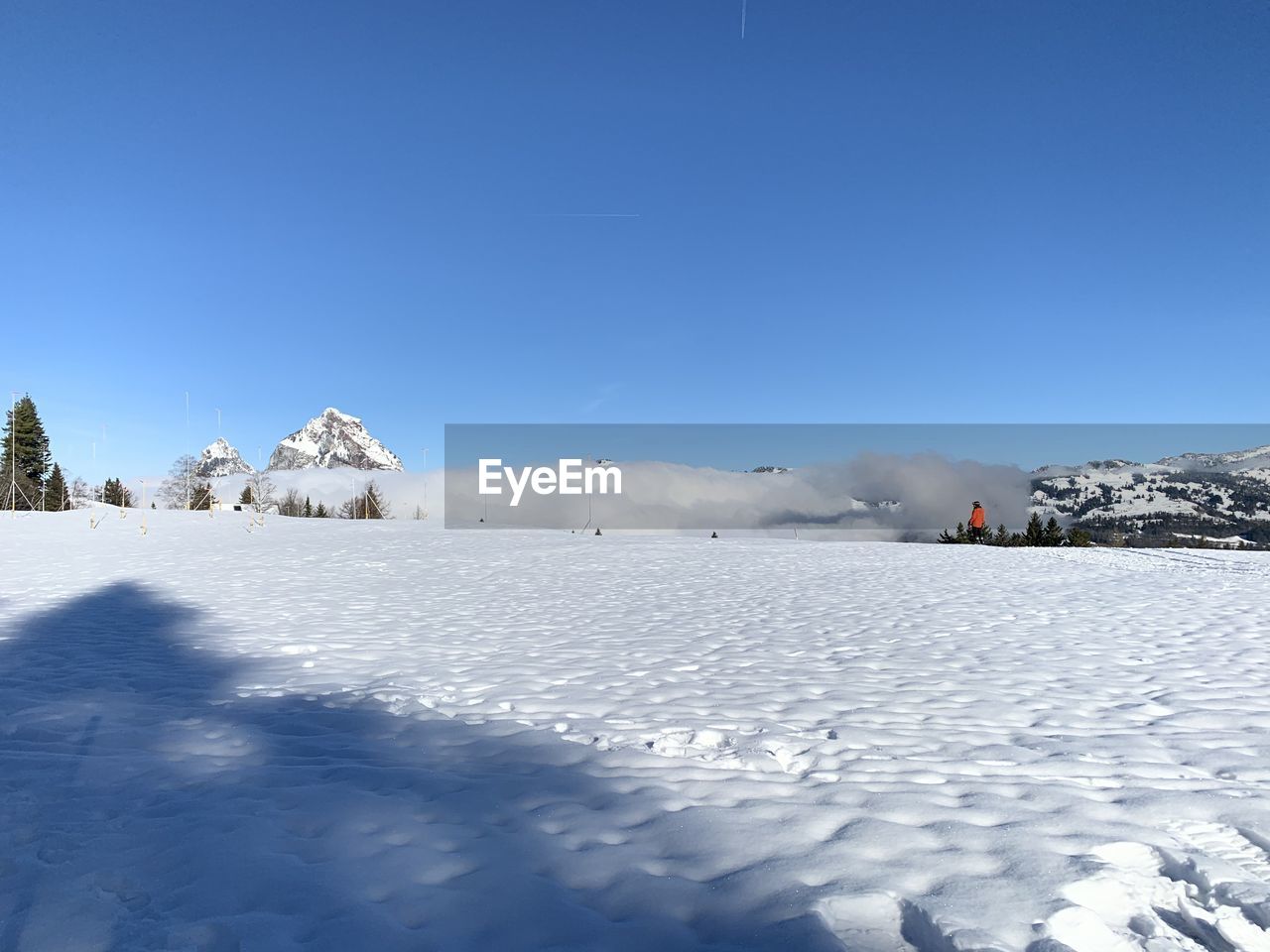 Snow covered landscape against blue sky