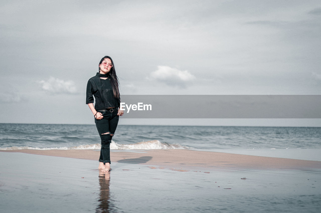 Full length of young woman standing on beach