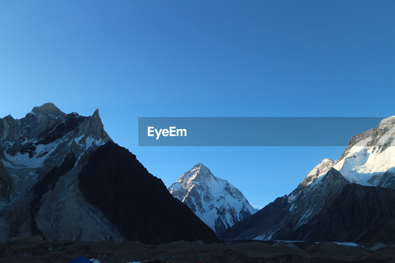 Scenic view of snowcapped mountains against clear blue sky