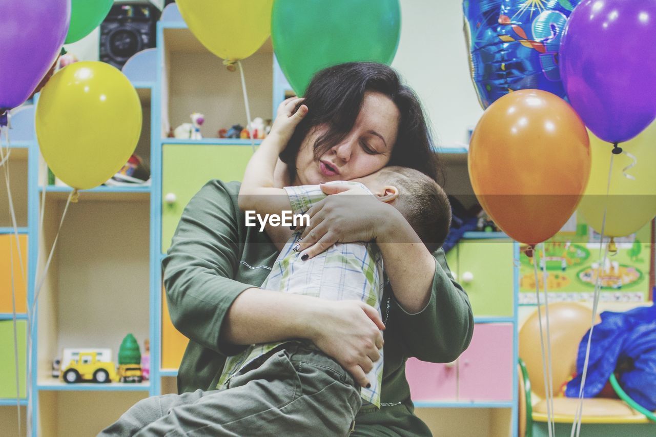 PORTRAIT OF SMILING YOUNG COUPLE AT BALLOONS AT HOME