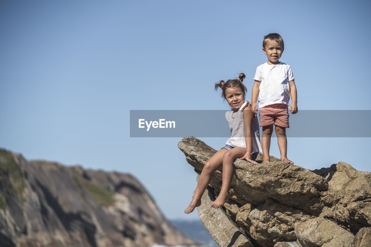 Cute sibling on flysch against blue sky