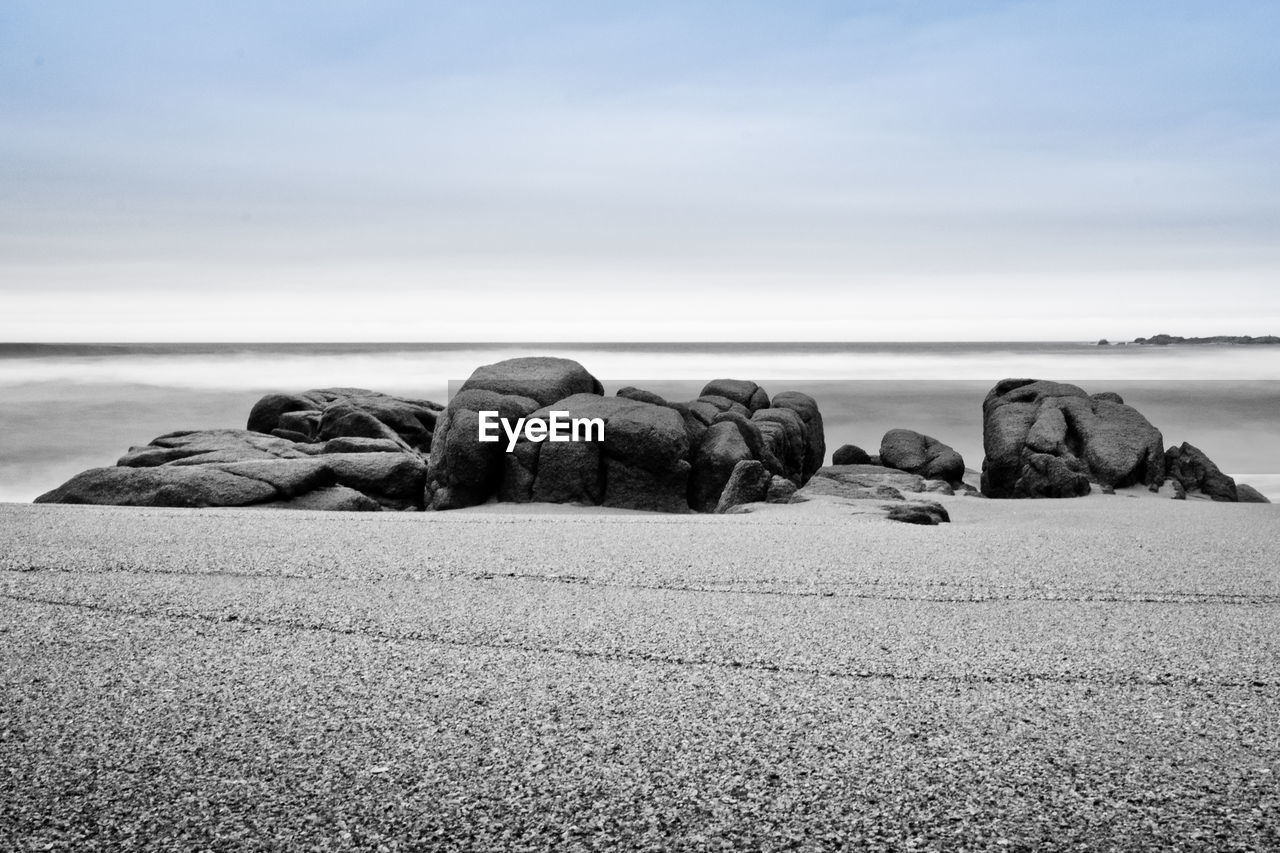 ROCKS ON SHORE AGAINST SKY