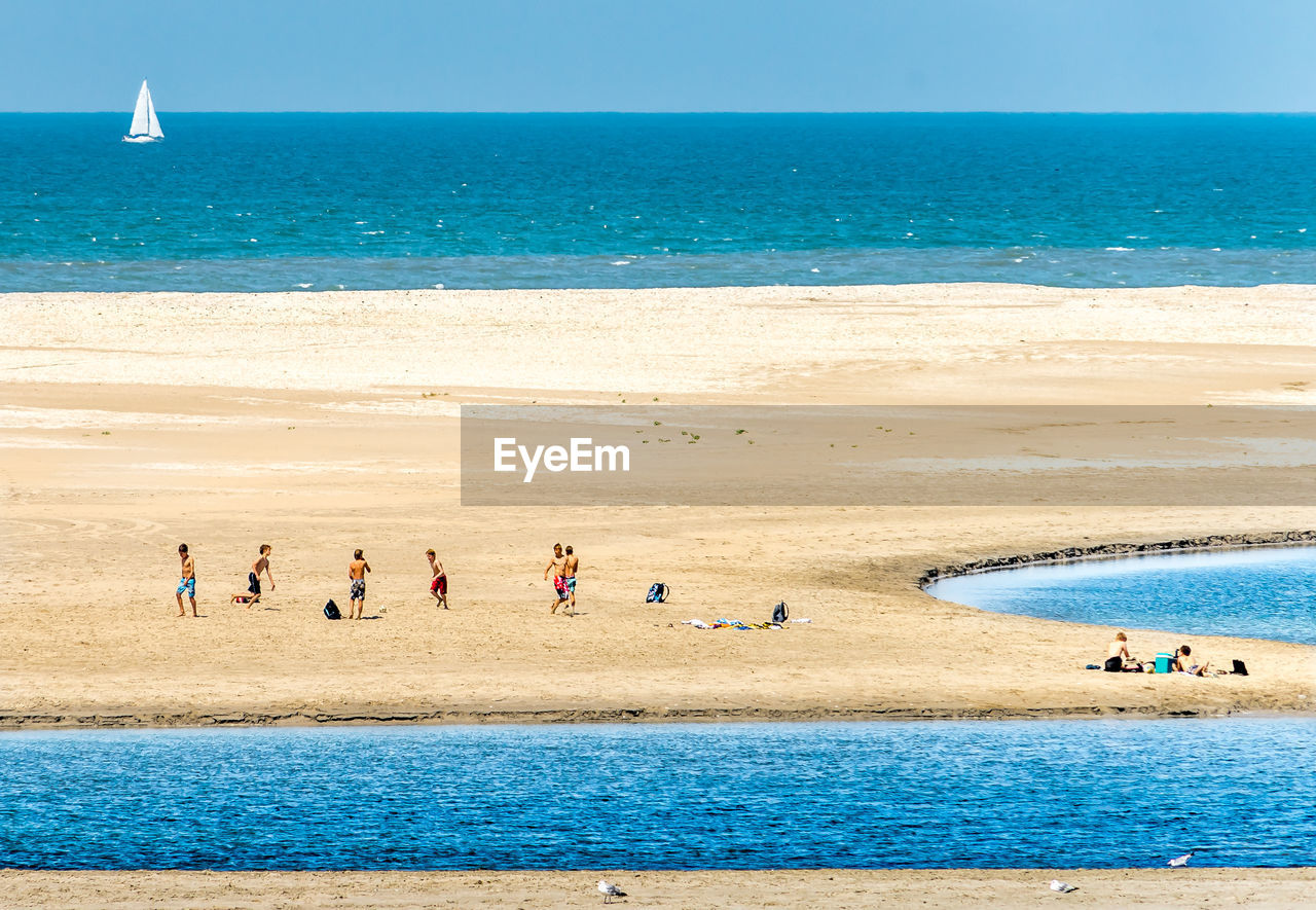 High angle view of children playing on sand at beach during sunny day