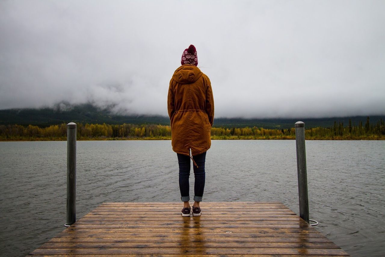 Rear view of woman standing on pier over lake vermilion at banff national park