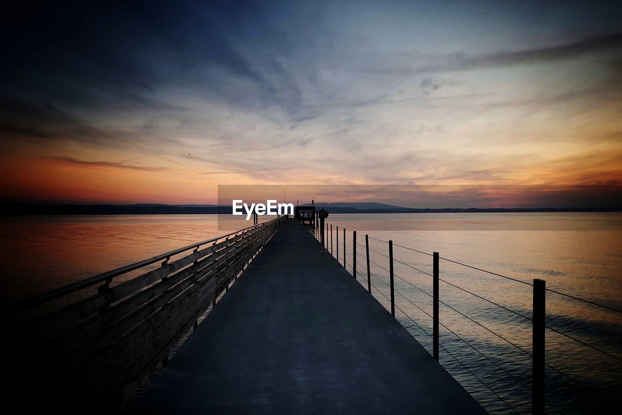 Pier over sea against sky during sunset