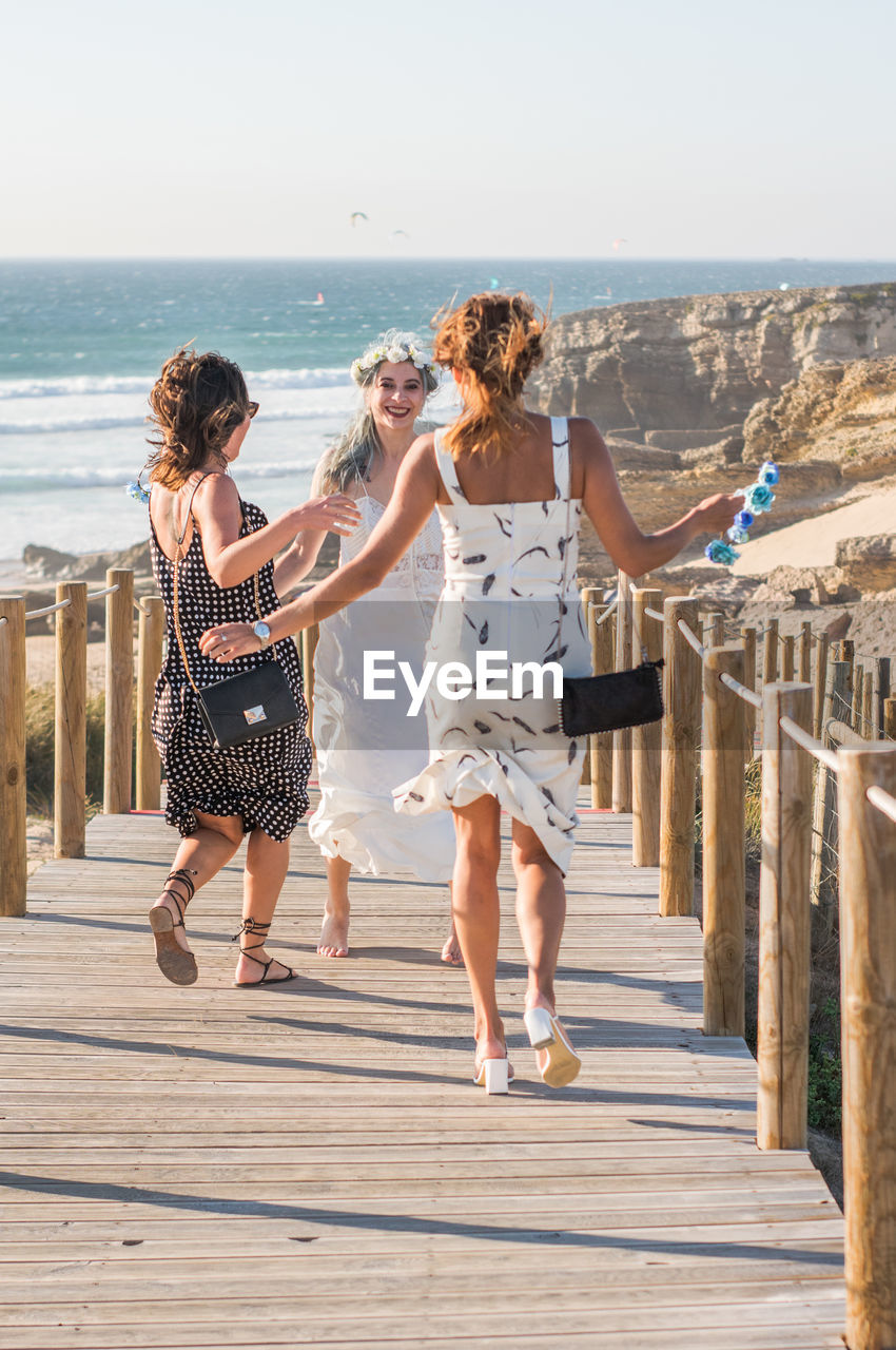 Happy women running towards friend on wooden footbridge