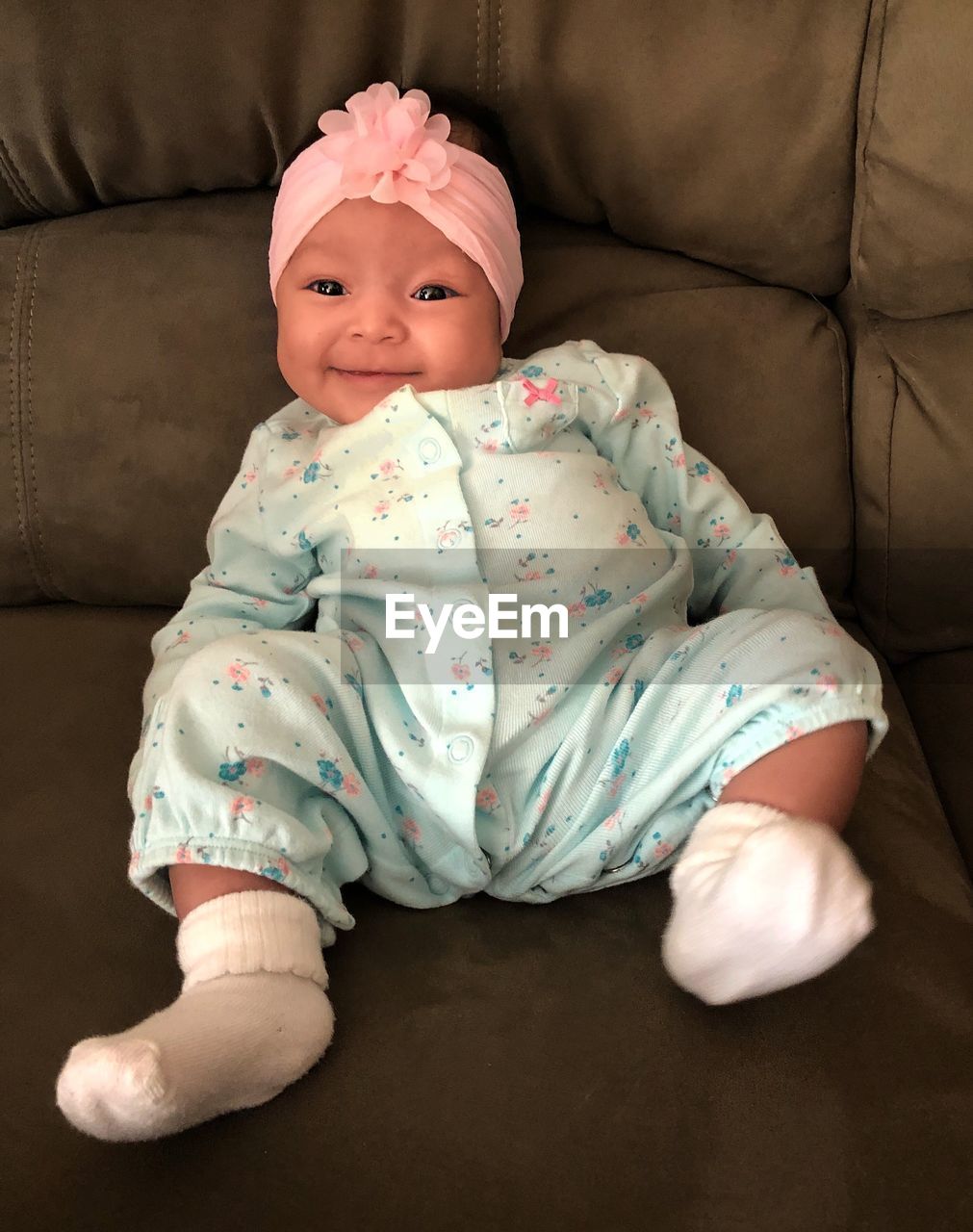 PORTRAIT OF BABY GIRL SITTING ON SOFA