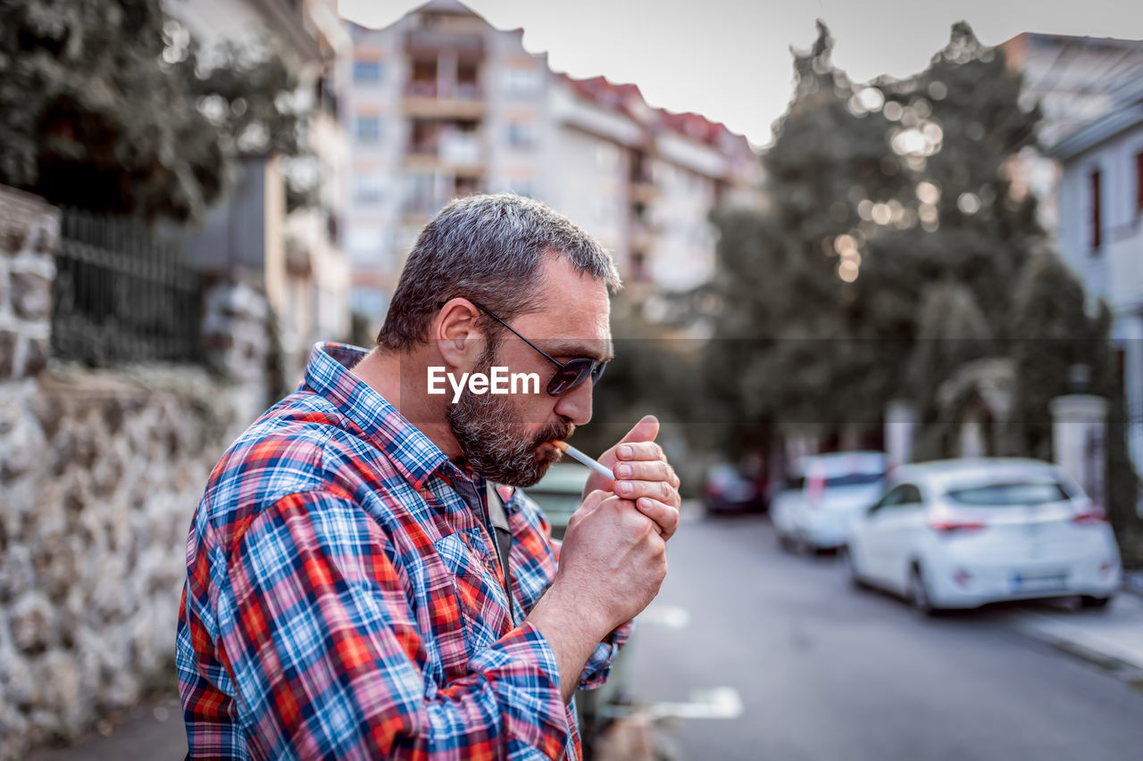 Portrait of handsome businessman. dressed man is relaxing with smoking a cigarette outdoors.