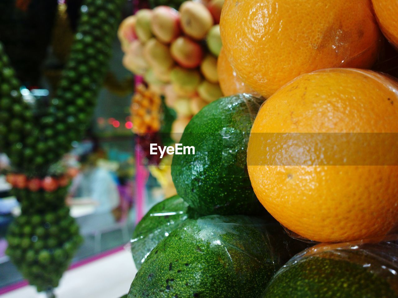 Close-up of oranges and avocados for sale at market stall