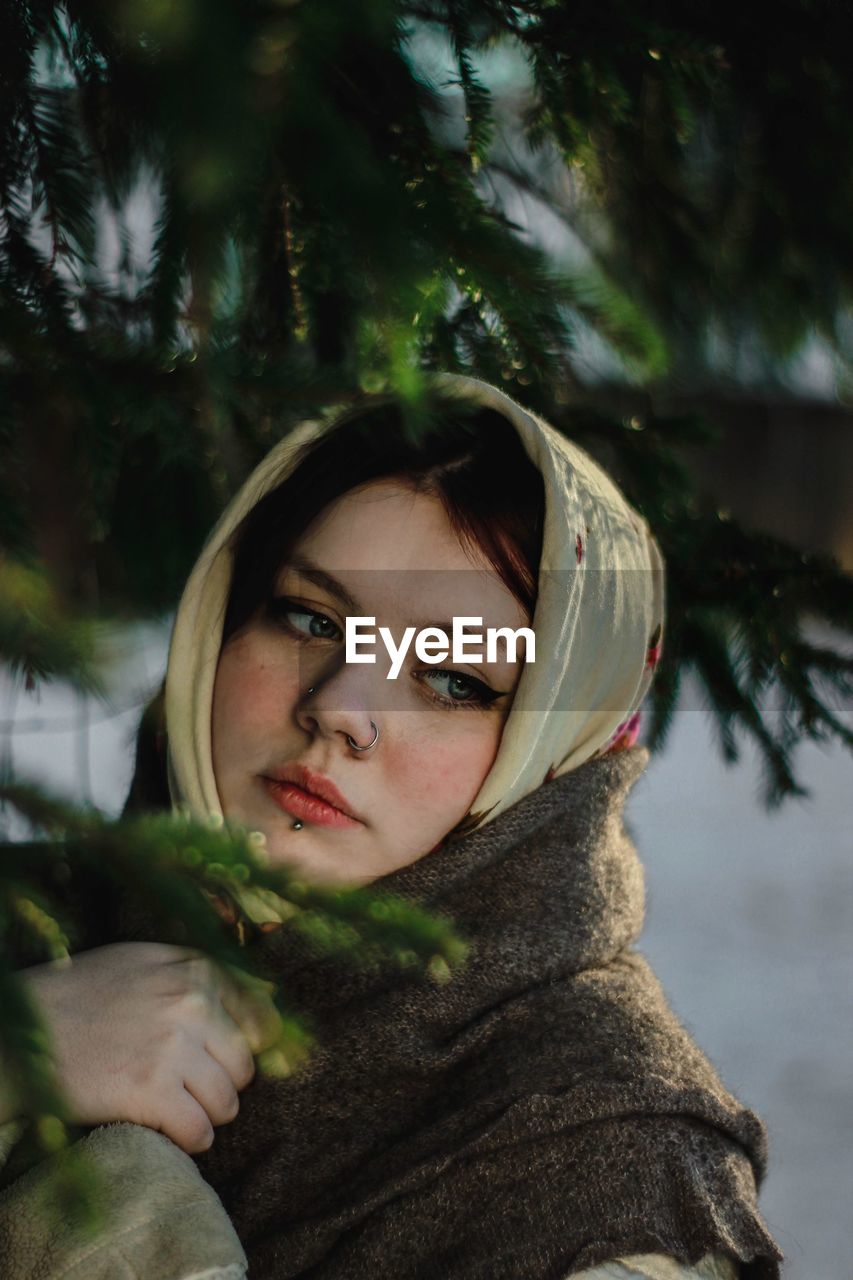 Close-up of woman wearing headscarf and shawl looking away by tree