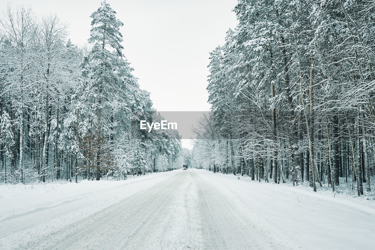 Snowy road in winter forest with moving car