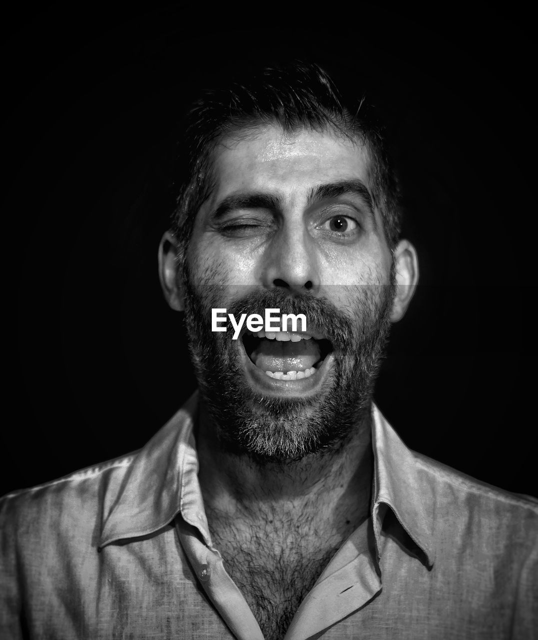 Portrait of man winking on black background