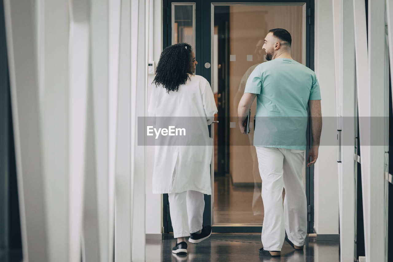 Rear view of male and female hospital staff walking towards door