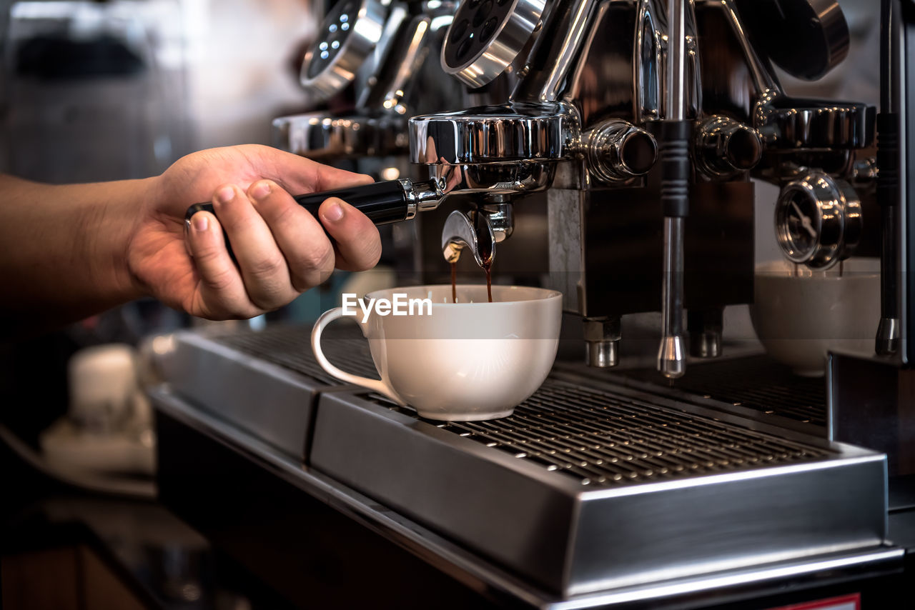 Coffee shop owner or barista using automatic coffee machines 